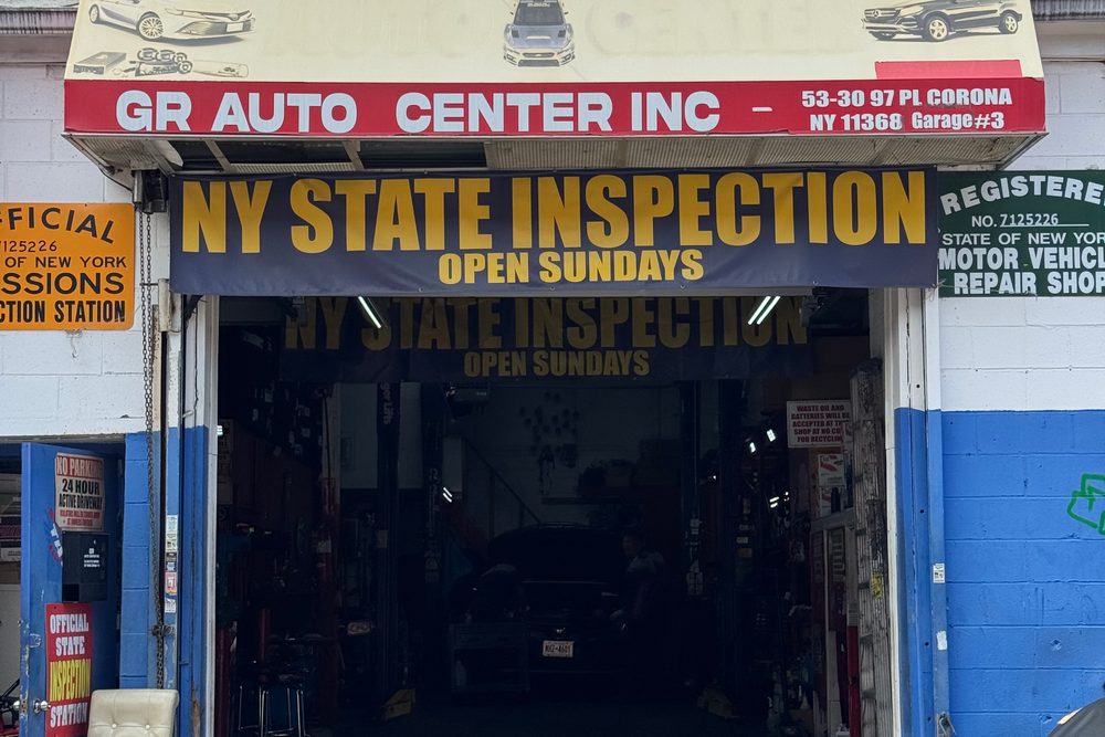 GR Auto Center's storefront on 97th Place: the red awning reading GR Auto Center Inc, 53-30 97 Pl, Garage #3, above the open service bay with the New York State inspection banner over the door.